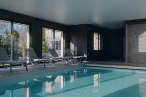 翁弗勒尔La Fraîchette-Hôtel & Spa的客房设有带椅子和窗户的游泳池。