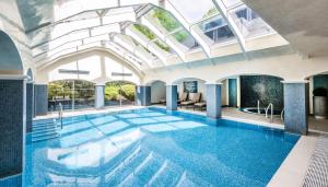 埃文河畔斯特拉特福Ettington Park Hotel, Stratford-upon-Avon的一座带玻璃天花板的建筑中的游泳池