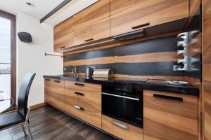 弗罗茨瓦夫Luxurious Apartments Walonska with underground GARAGE by Renters的厨房配有木制橱柜和黑烤箱。