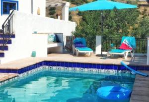 阿尔姆尼卡Algarrobo Azul的一个带两把椅子和遮阳伞的游泳池