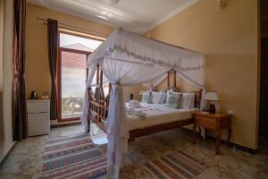 乌罗阿Sunny Palms Beach Bungalows的一间卧室设有天蓬床和窗户。