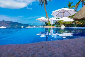 曼萨尼约Mar Celeste的一个带白色遮阳伞的游泳池,并享有海景。