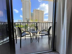 檀香山Aqua Palms 306 condo的阳台配有桌椅,享有城市美景。