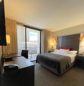 檀香山Aqua Palms 306 condo的配有一张床和一张书桌的酒店客房
