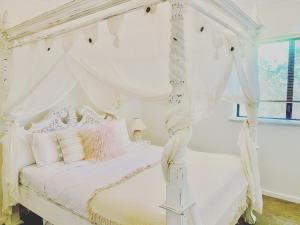 格纳拉巴普Ombak Beach Villa ~ Margaret River的卧室内的白色天蓬床和白色窗帘