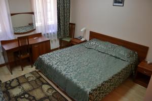 喀山布拉克酒店的一间卧室配有一张床、一张书桌和一面镜子