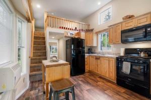 阿什福德New Tiny Home Steps Away From Mt. Rainier的厨房配有黑色冰箱和木制橱柜。