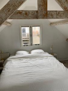 滨海贝亨zilvermeeuw的窗户客房内的一张白色床