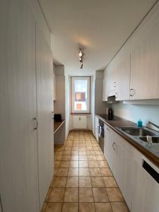 迪森蒂斯Ferienwohnung Dorfzentrum的厨房配有白色橱柜和瓷砖地板。