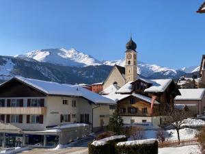 迪森蒂斯Ferienwohnung Dorfzentrum的一座村庄,有教堂和雪覆盖的群山