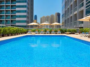 迪拜Armada Avenue Hotel - formerly Armada BlueBay Hotel的大楼内带椅子和遮阳伞的大型游泳池