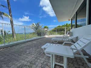 帕诺滩Studio BTS - Lauderdale-By-The-Sea的一个带白色椅子的庭院和一个海景阳台。
