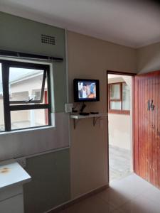 BizanaEmampingeni lodge的一间设有门的房间和墙上的电视