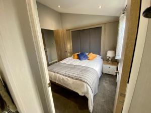纽基ELITE BLUE LUXURY 3 BEDROOM LODGE NEWQUAY, CORNWALL的一间卧室配有带橙色和蓝色枕头的床