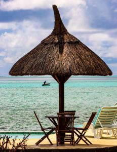 马埃堡CHILLpill Guest House的海滩上的一把草伞和椅子