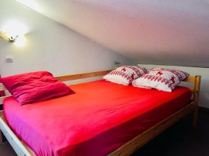 里蒙纽耶Les Menuires skis aux pieds的一张带红色和白色枕头的床