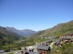 里蒙纽耶Les Menuires skis aux pieds的享有山谷美景,设有房屋和山脉