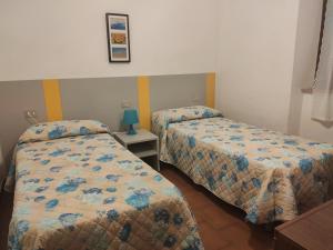 波蒙特Appartamento Il Girasole的一间卧室配有两张床和一张带台灯的桌子