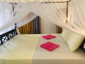 乌纳瓦图纳Coral Palm Villa and Apartment的一张带两个红色枕头的白色床