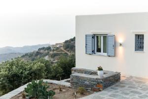 伊利达Cycladic Villa with sea view!的白色的房子,设有蓝色的窗户和山脉