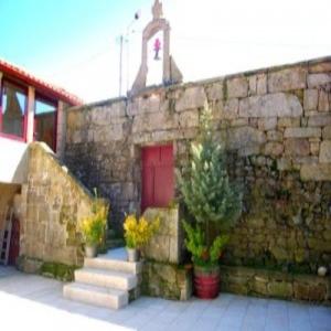 GralhasCasa Do Seminario的一座石头建筑,有红色的门和一些植物
