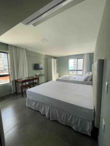 纳塔尔Ilusion flat Ponta Negra的卧室配有一张白色大床和一张书桌