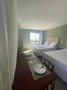 纳塔尔Ilusion flat Ponta Negra的酒店客房设有两张床和一张带盘子的桌子。