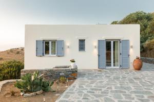 伊利达Cycladic Villa with sea view!的白色的房子,上面有蓝色百叶窗