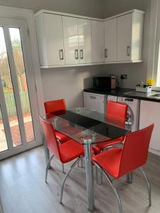 巴洛赫Nairoo的厨房配有玻璃桌和红色椅子