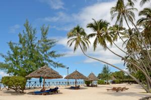 普瓦尼梅查恩加尼海洋天堂Spa度假酒店的海滩上设有遮阳伞和椅子,棕榈树