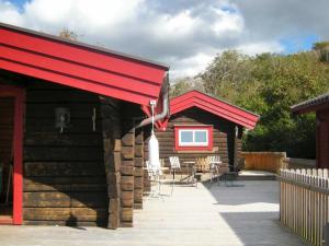 Hälleviksstrand9 person holiday home in H LLEVIKSSTRAND的小木屋设有红色遮阳篷和桌椅