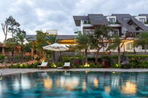 Buôn JuHami Garden - Authentic & Natural Resort的大楼前设有游泳池的酒店