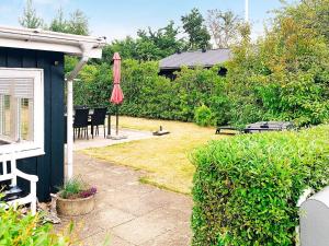 布罗艾厄4 person holiday home in Broager的庭院配有遮阳伞和桌椅。