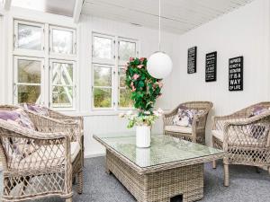 Nørby6 person holiday home in Ringk bing的一间设有柳条椅和花瓶的桌子的房间