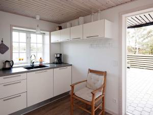 凡岛4 person holiday home in Fan的厨房配有白色橱柜、椅子和窗户