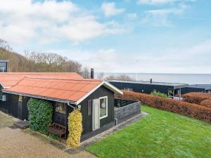 森讷比5 person holiday home in Juelsminde的庭院里一座带橙色屋顶的小房子