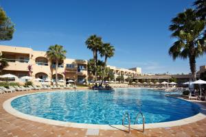 圣埃乌拉利亚格鲁桑塔艾拉Spa酒店（仅限成人入住）的度假村的游泳池拥有棕榈树和遮阳伞
