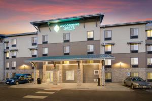 布鲁姆菲尔德WoodSpring Suites Broomfield-Westminster的停车场内有车辆的旅馆