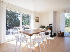 莱斯7 person holiday home in L s的一间带木桌和白色椅子的用餐室