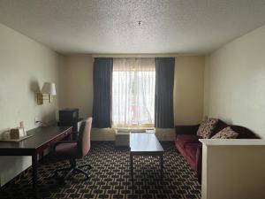 FairfieldBudgetel Inns & Suites的酒店客房设有一张桌子、一张沙发和一个窗口。