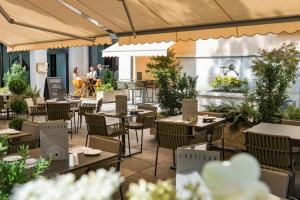 日内瓦Hotel Rotary Geneva - MGallery的户外餐厅设有桌椅,背景为人。