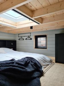 许尔斯霍斯特Nieuw! Sfeervol Tiny House in de natuur en aan het water的卧室设有一张木制天花板上的大床