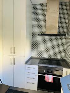 里斯本Lovely Apartment to feel Lisbon的厨房配有白色橱柜和黑炉。