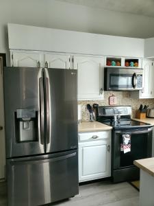 印第安纳波利斯Cozy Indy Home的厨房配有不锈钢冰箱和白色橱柜