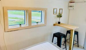 维泽桑讷Dancamps Holmsland的一间设有一张床、一个窗口和两个凳子的房间