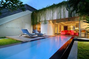 塞米亚克Bali Island Villas & Spa CHSE Certified的一个带两把椅子的游泳池以及一座房子