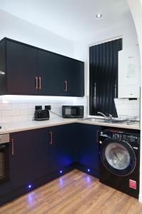 利兹Kitchener house的厨房配有黑色橱柜和洗衣机。