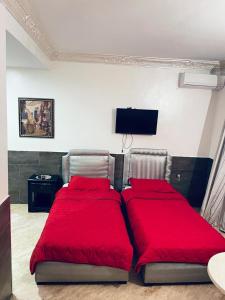 卡萨布兰卡SINGAPOUR MAROC的一间卧室配有两张带红色床单的床和一台平面电视