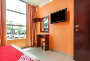 怡保My Town Hotel的一间卧室设有橙色的墙壁、一张桌子和电视。