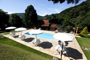 圣安东尼奥-杜皮尼亚尔Pousada Alpes的一个带遮阳伞和椅子的游泳池以及一座房子